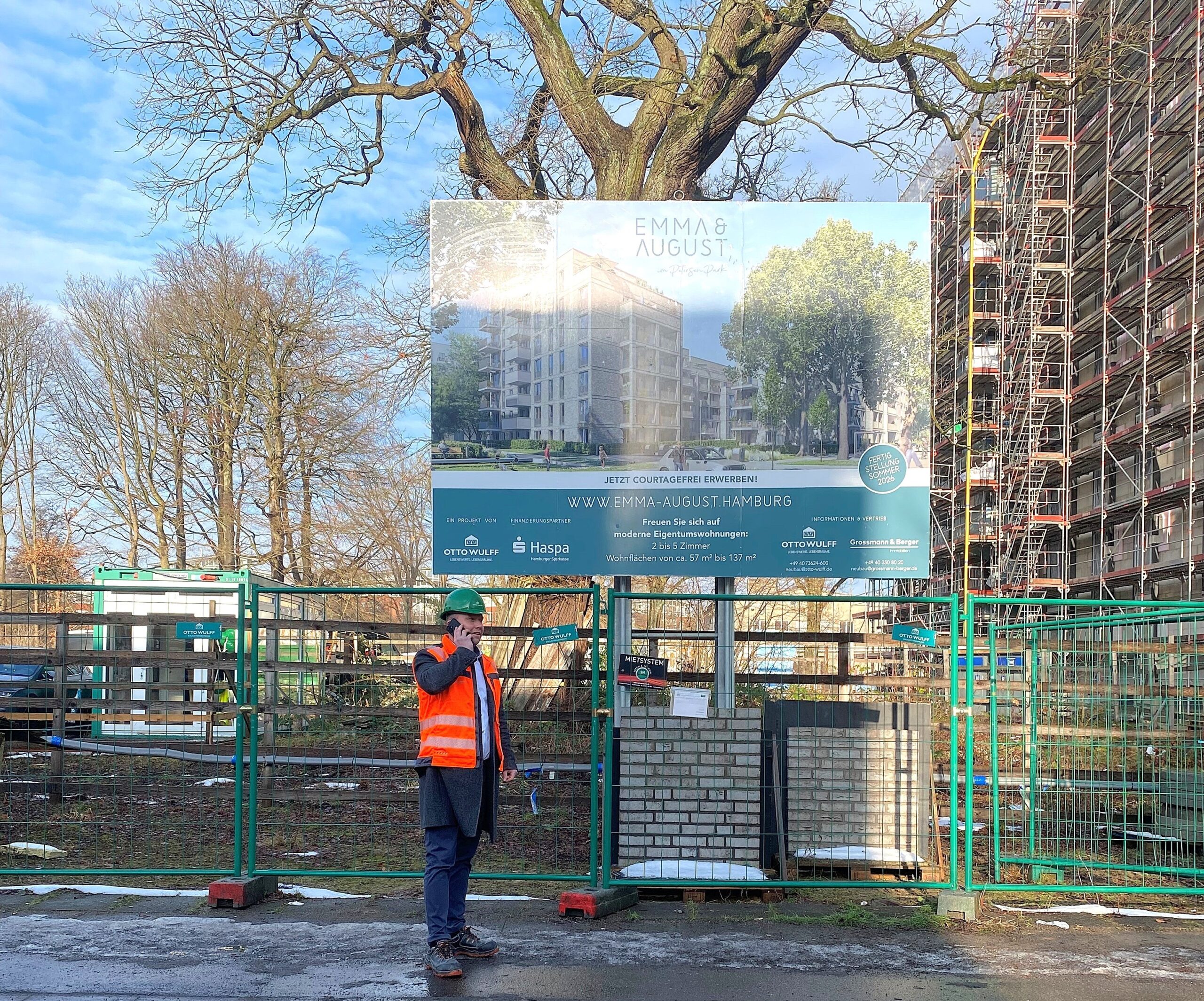 Baustelle mit Bauarbeiter vor Werbeschild für neue Wohnungen in Hamburg.
