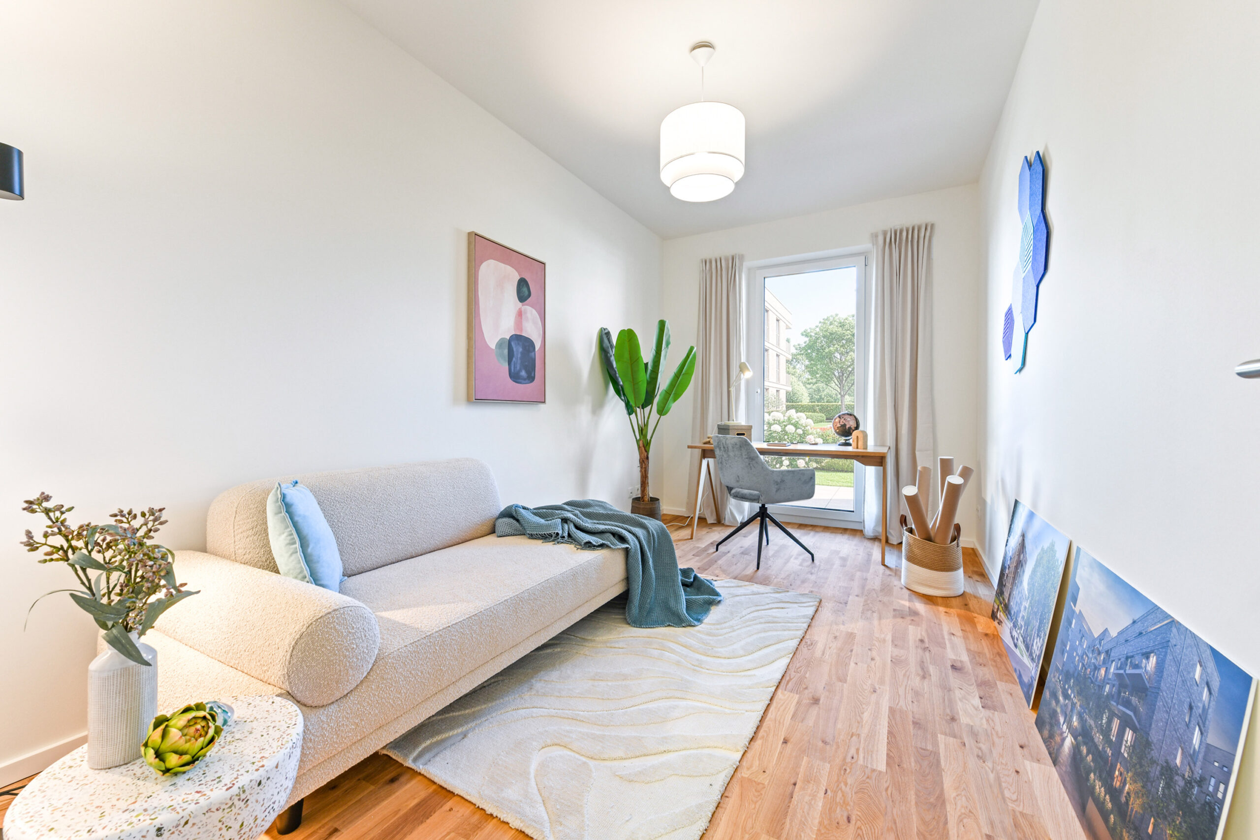 Helles Arbeitszimmer mit Sofa, Schreibtisch am Fenster und moderner Dekoration.
