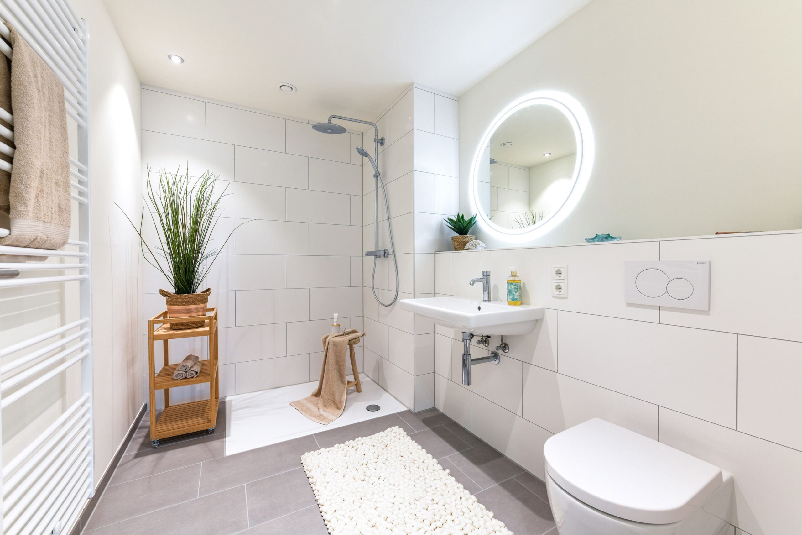 Modernes, helles Bad mit Dusche, WC, Spiegel, Waschbecken und Pflanzen.