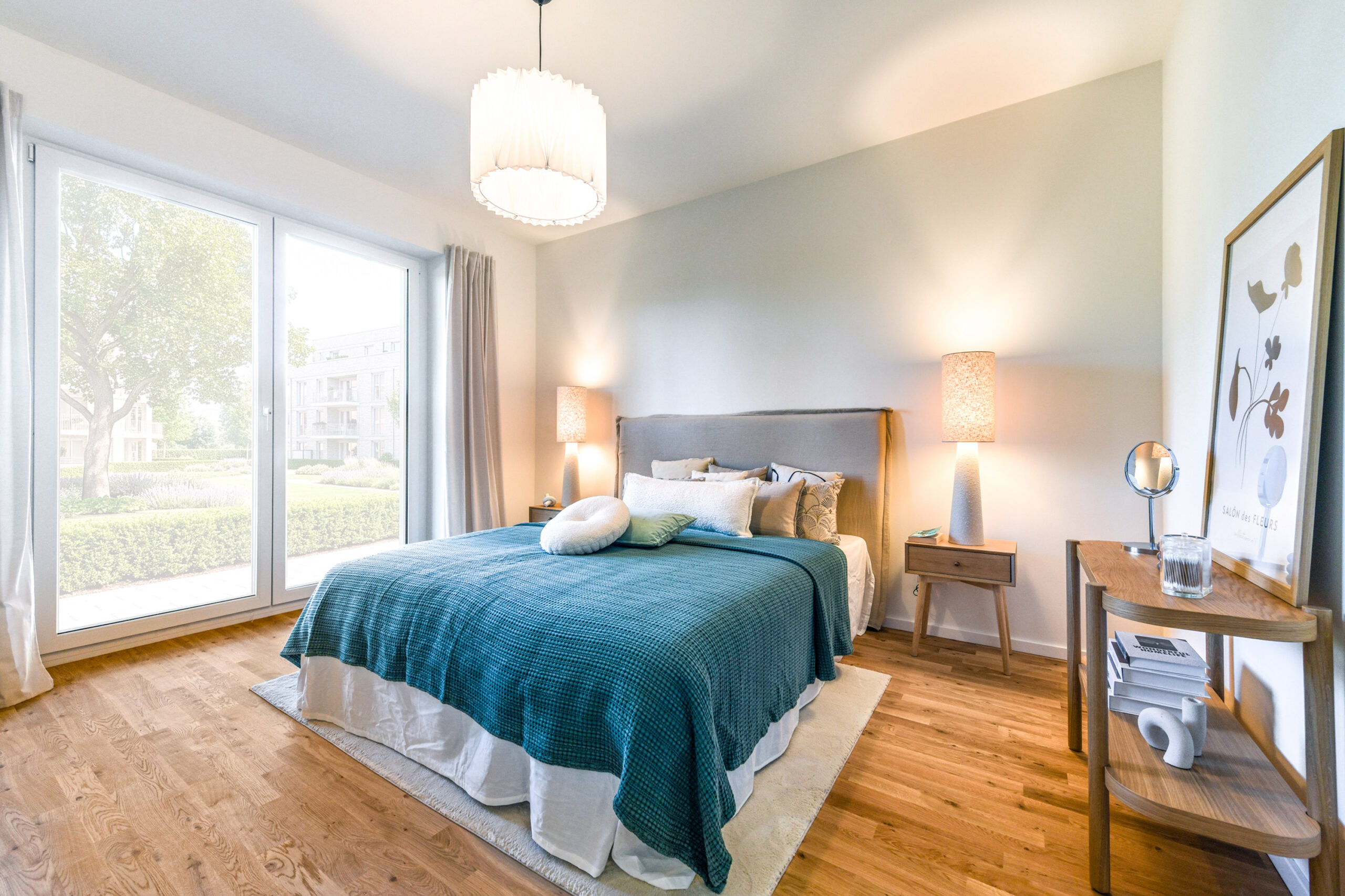 Helles Schlafzimmer mit großem Bett, Holzfußboden und großen Fenstern.